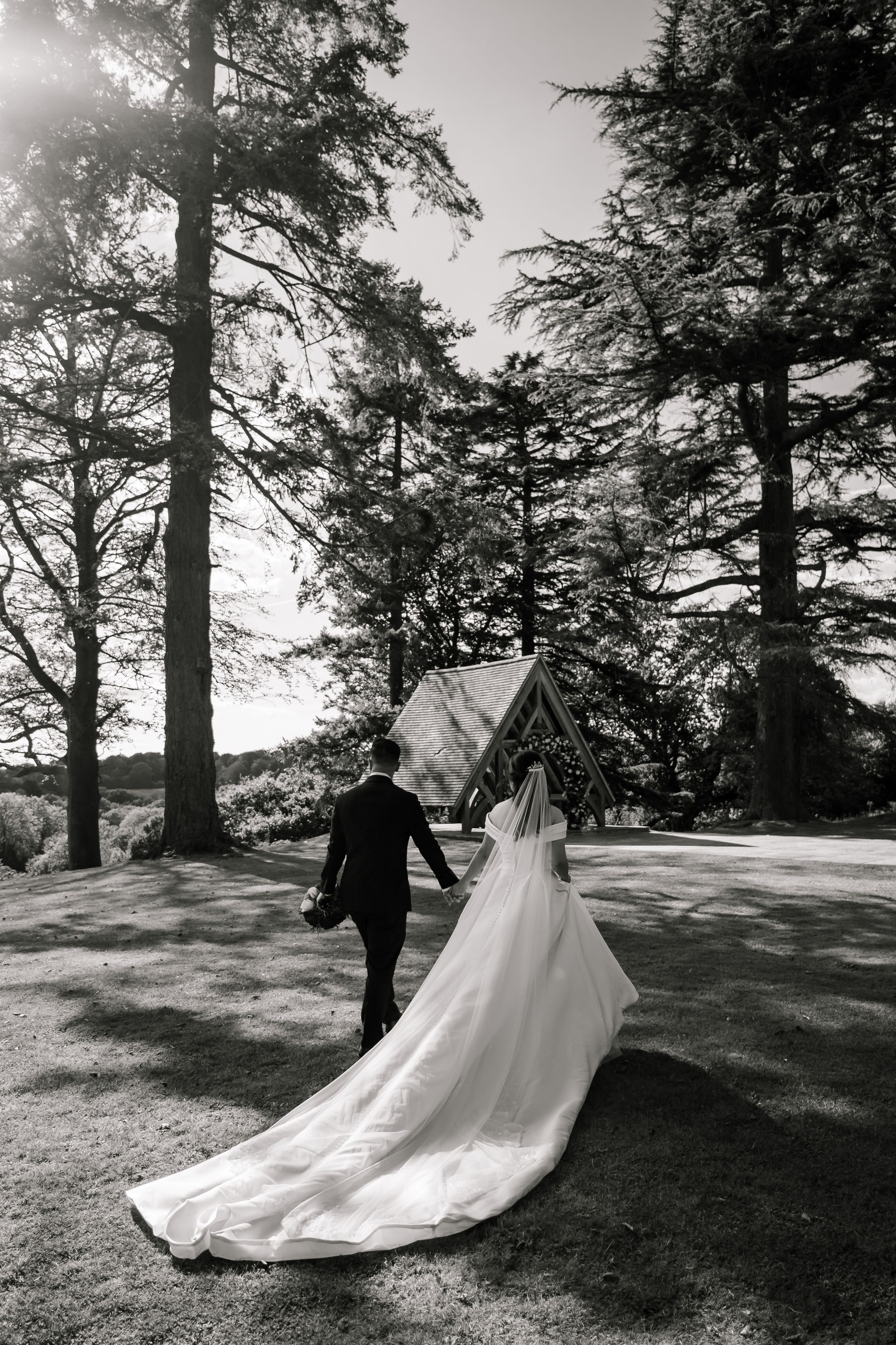 A romantic wedding sequence showing a couple walking among tall trees in a dreamy black and white forest setting.