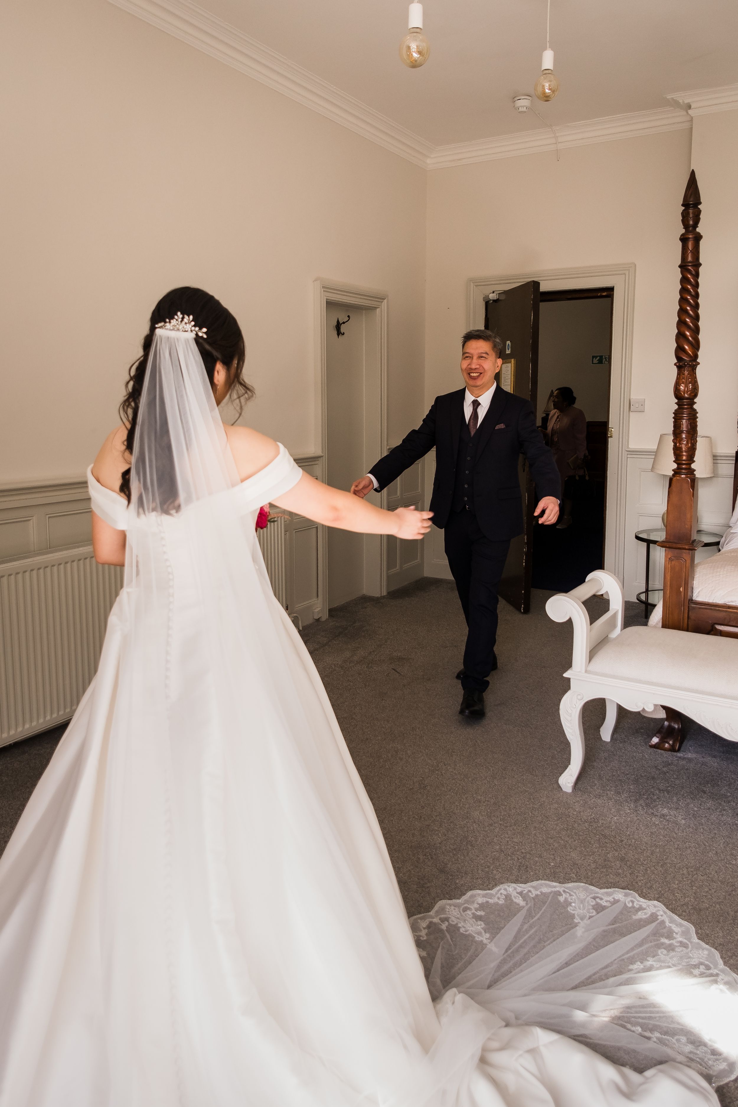 A flowing white wedding dress twirls gracefully across a carpeted room with natural lighting streaming through windows.