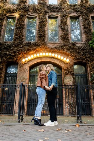 A woman and her wife kiss under iconic downtown Seattle Washington lights