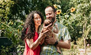 a woman and a man looking at their newborn smiling outside in the sun in Walla Walla