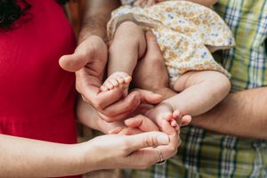 A woman and man gently hold their newborns feet