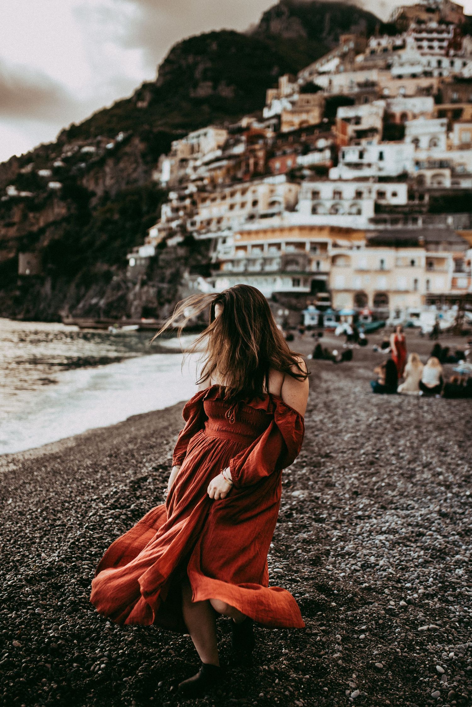 A woman twirling her wine color dress in the coastal town of Positano Italy.