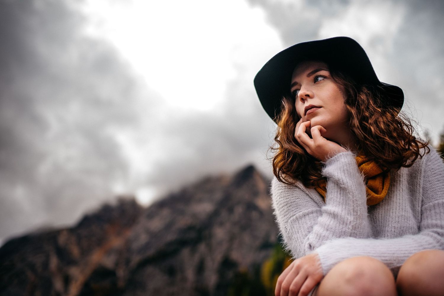 A Senior girl sitting on a boat with the mountains behind her at Lago Di Braies, the Dolomites, In Italy.