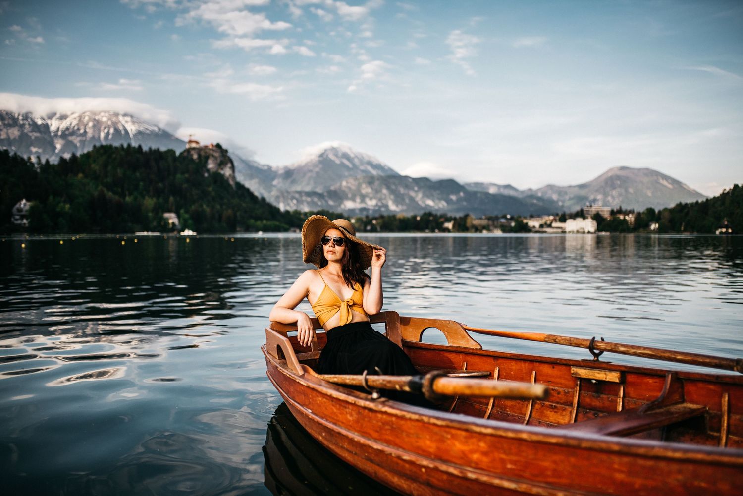 A woman posing in boat with a hat at Lake Bled in Slovenia.