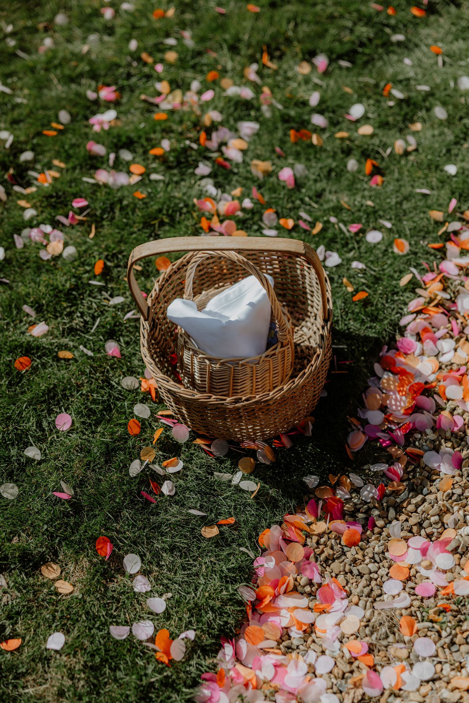 Wedding party celebrates with colorful confetti toss in outdoor garden setting during summer celebration.