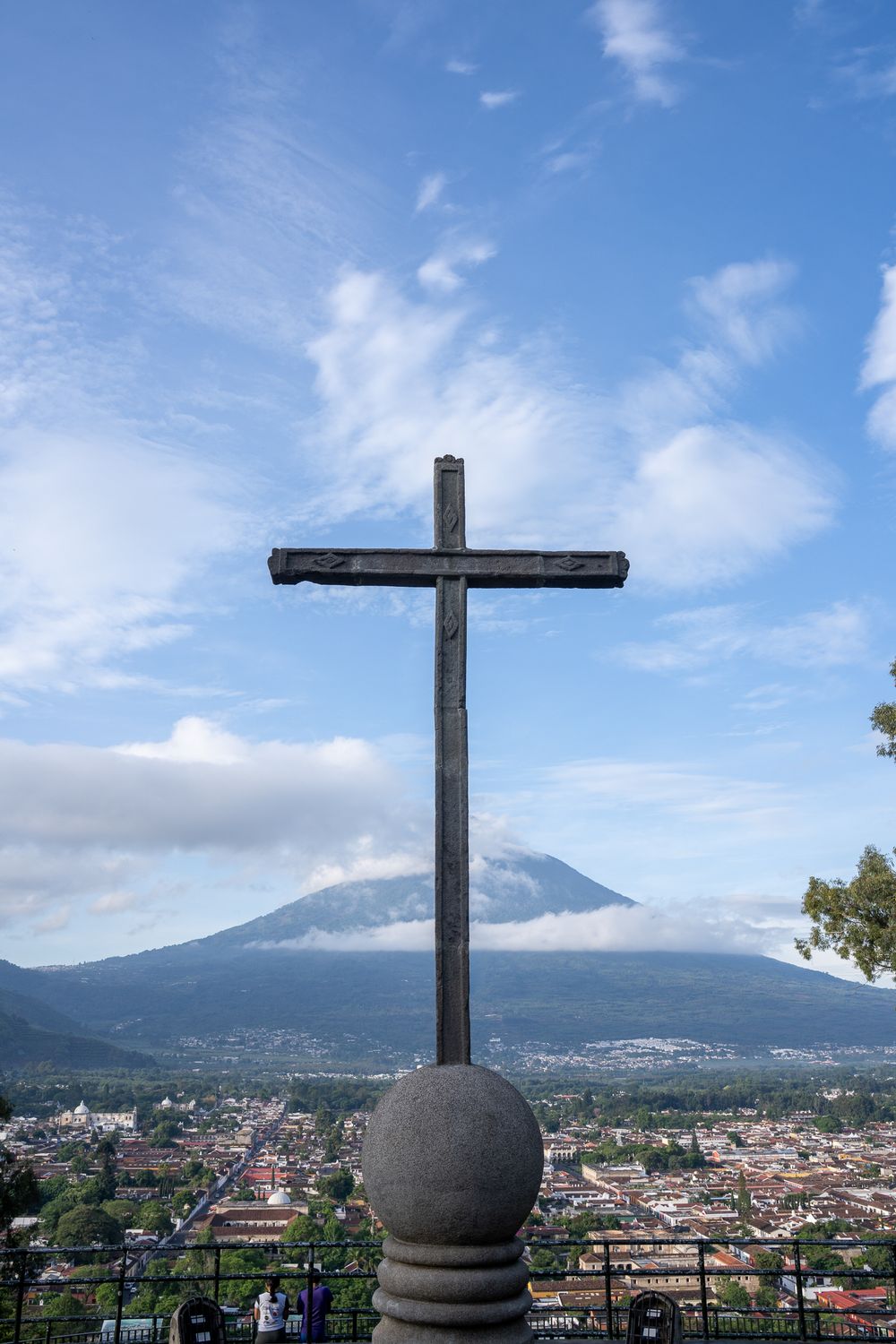 A series of panoramic views of Antigua Guatemala with a cross silhouette and Agua Volcano in the background against blue skies.