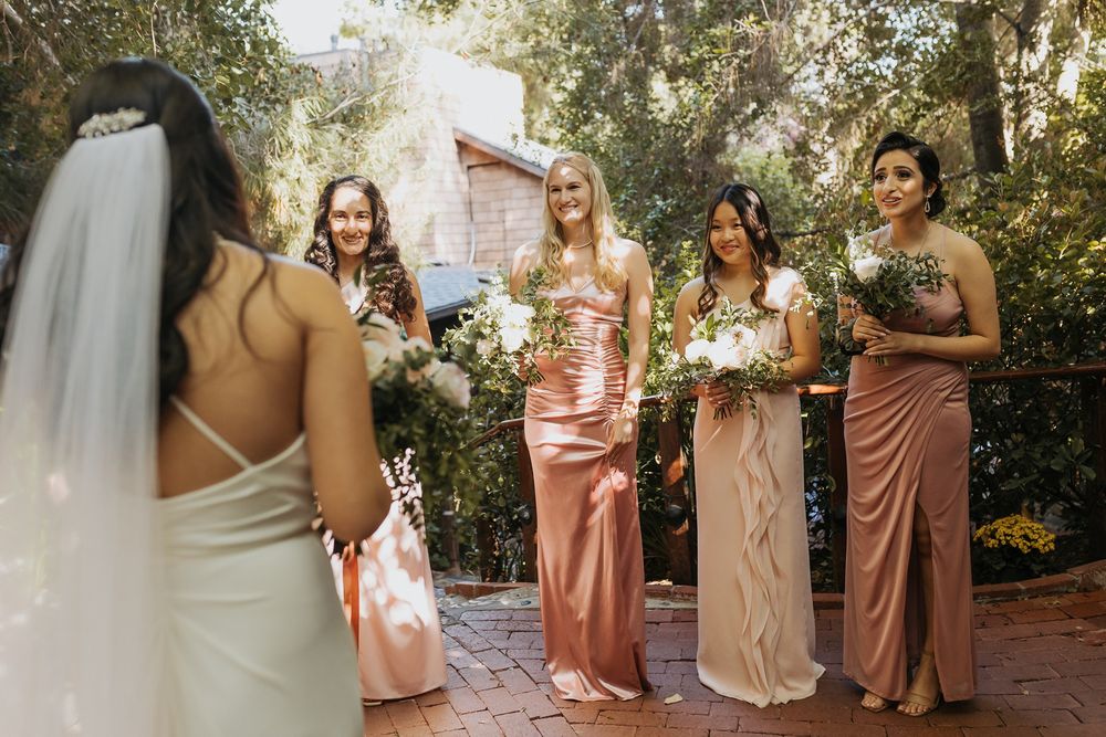 Bridesmaids in blush and champagne colored dresses see the bride for the first time Inn of the Seventh Ray in Topanga, California.
