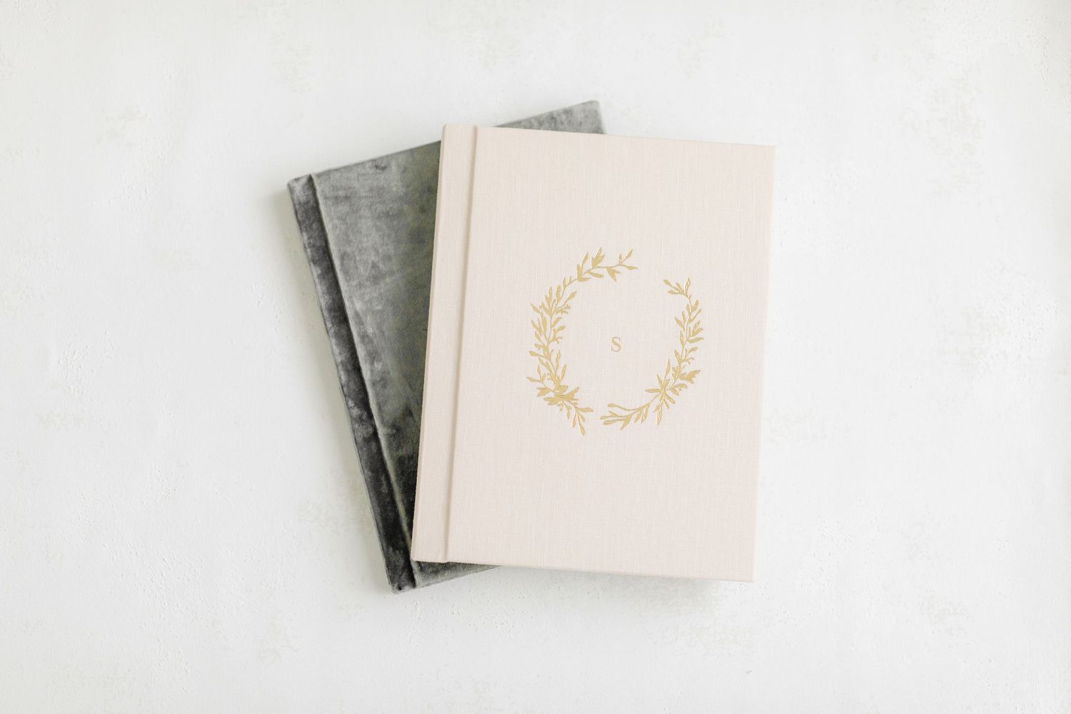 Elegant minimalist white wedding invitations with gold floral details arranged on a light marble surface.
