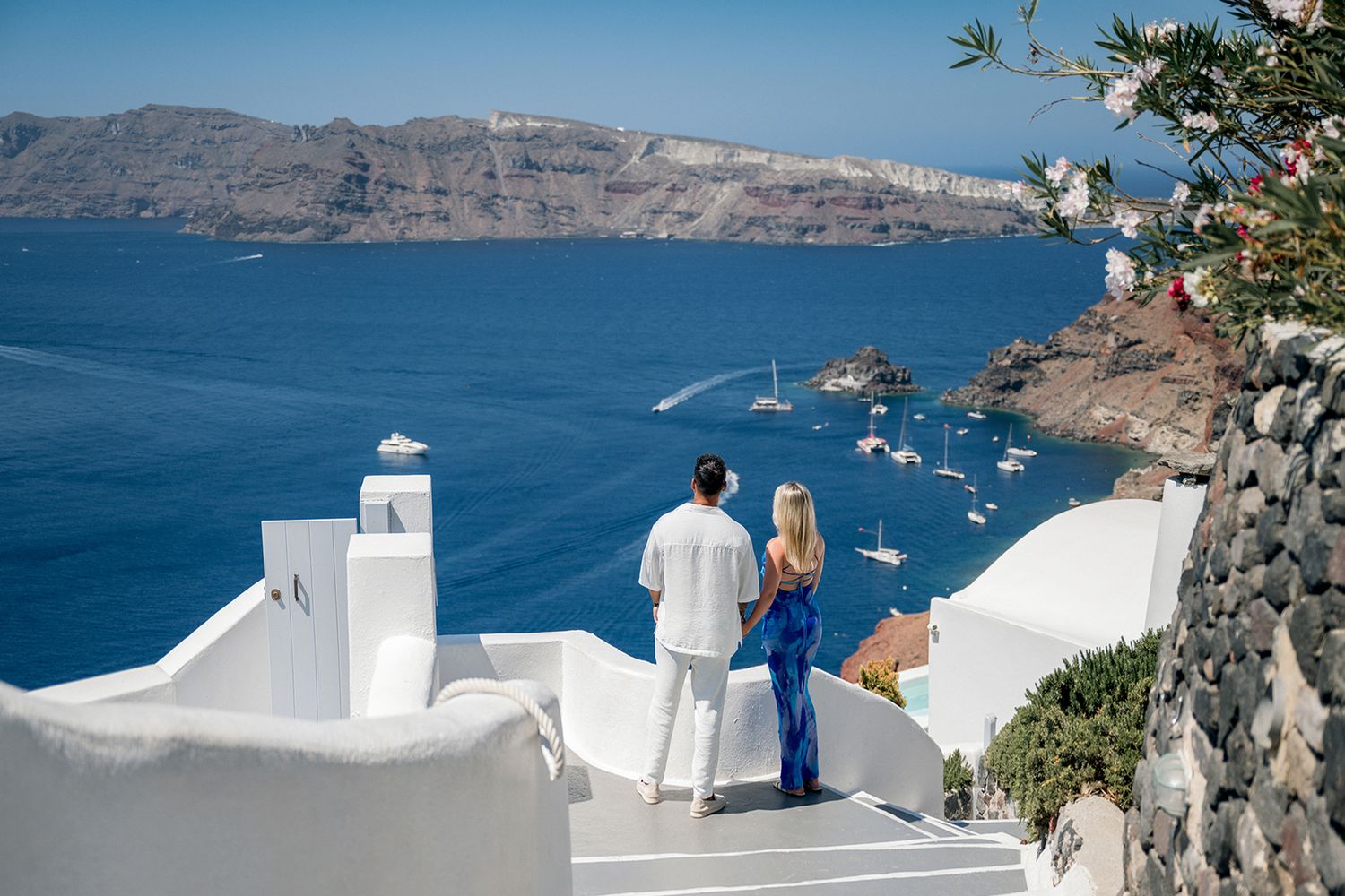 Panoramic view of white buildings and blue domes overlooking the Mediterranean Sea in Santorini, Greece.