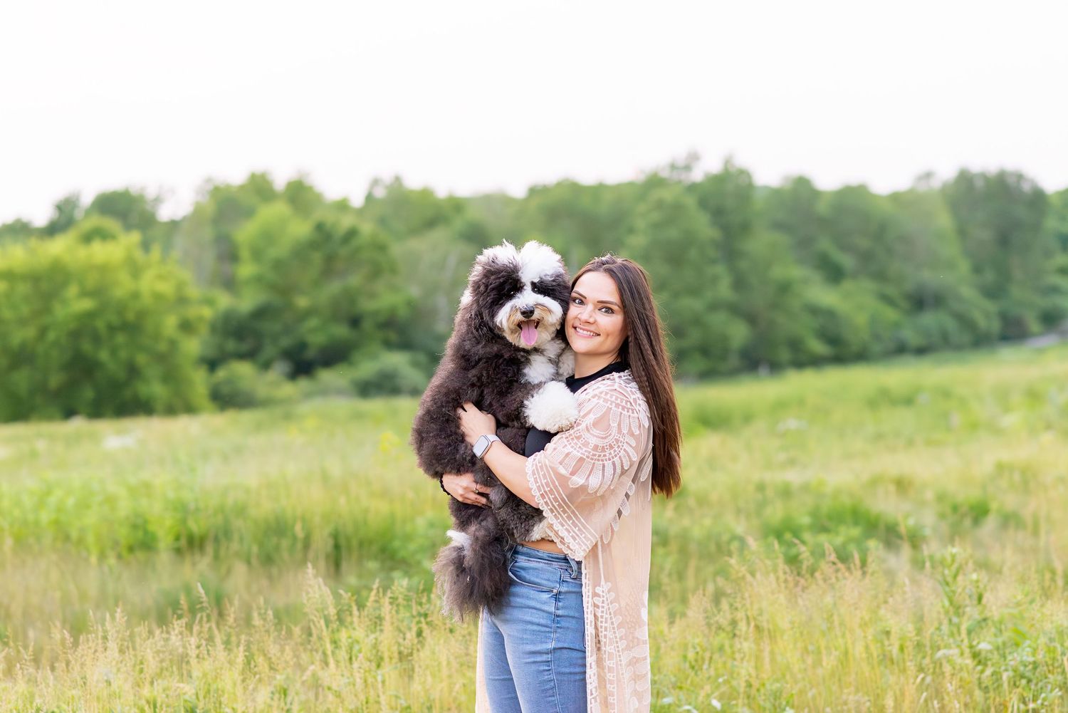 A couple embraces in a lush green field during a romantic outdoor photoshoot.