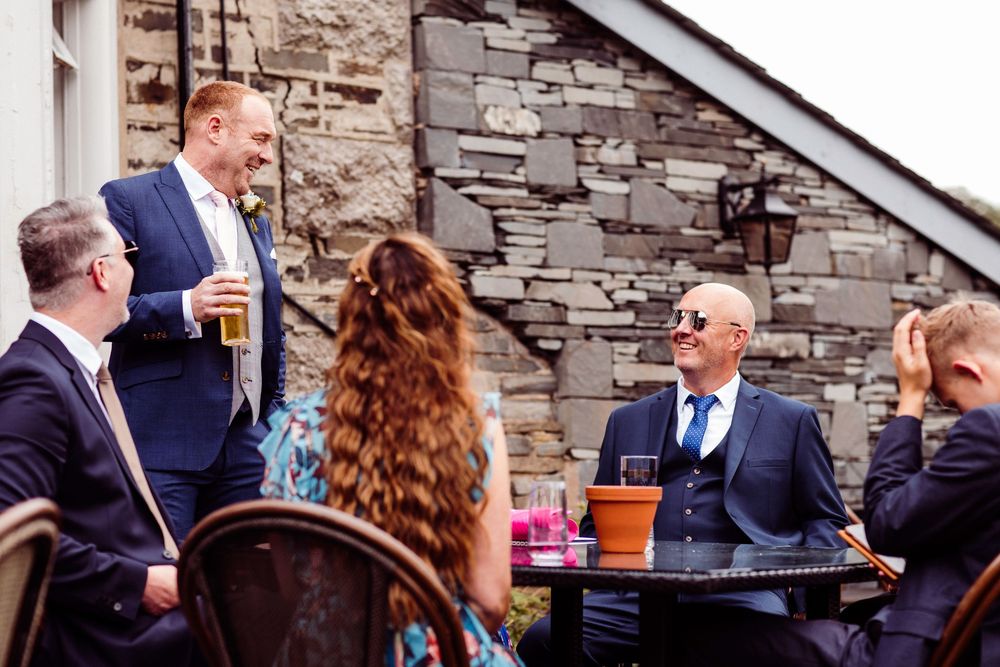 Wedding guests enjoy drinks and conversation on an outdoor stone patio during a reception celebration.