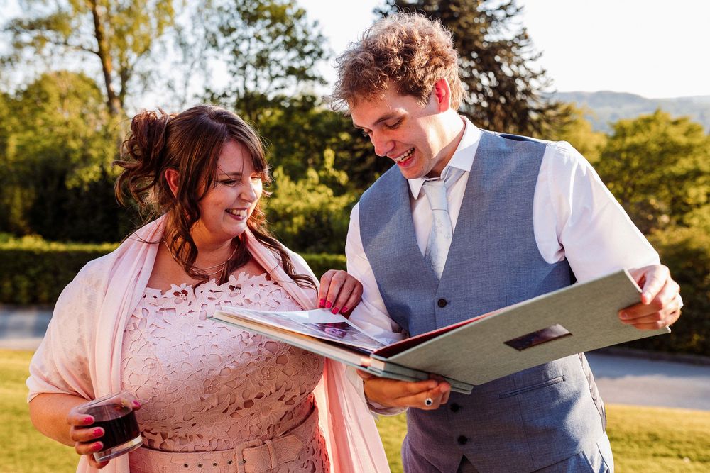 A couple shares a tender moment while looking through a photo album together outdoors during golden hour.