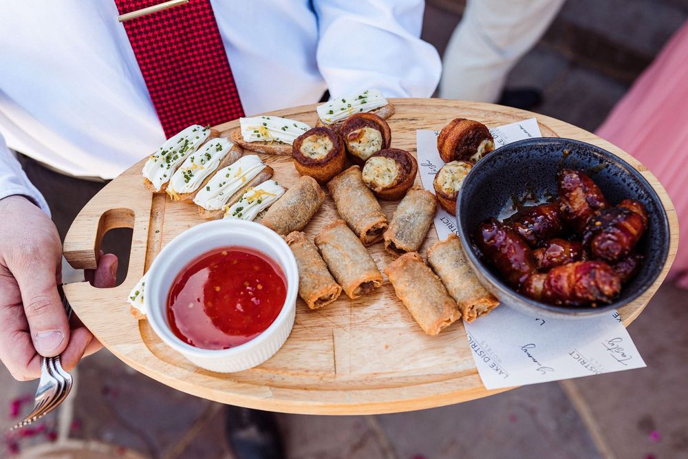 A wooden serving board displays various appetizers including meatballs, bread, and dipping sauces arranged in small bowls.