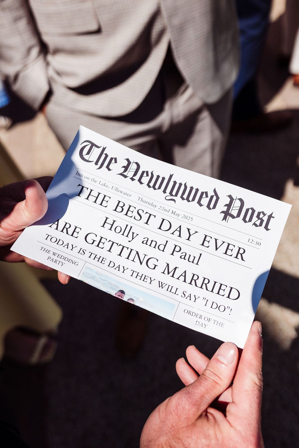 Hands holding a custom newspaper wedding announcement with 'The Best Day Ever' headline in The Newlywed Post style.