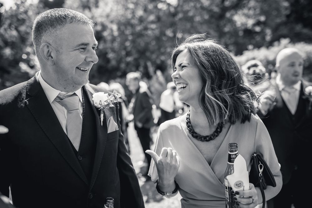 A collection of candid black and white wedding moments showing joyful interactions between guests and couples at an outdoor celebration.