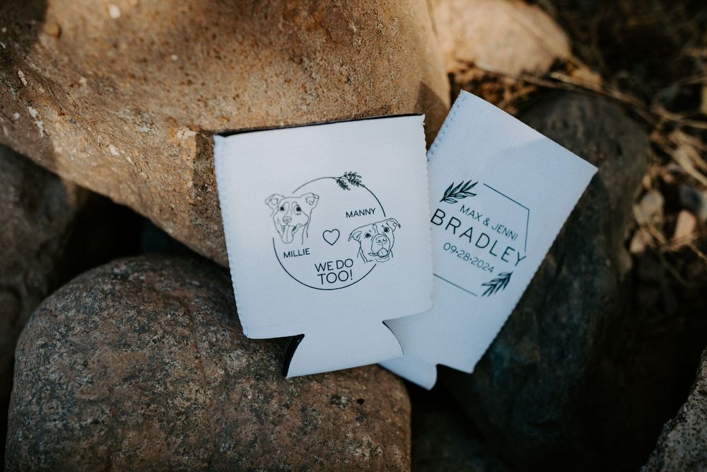 Custom wedding koozies and paper goods displayed on natural stone surface.