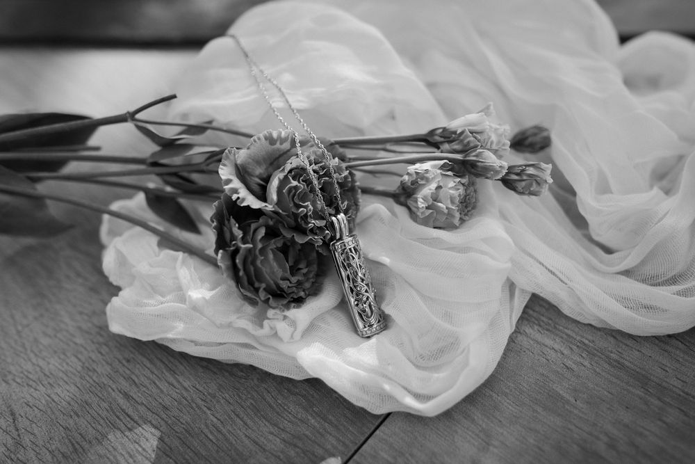 Black and white photo of dried flowers resting on delicate white fabric.