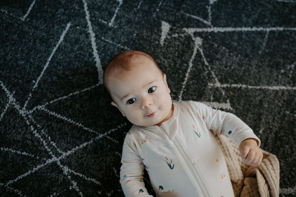 Baby lying on dark textured surface with chalk-like markings.