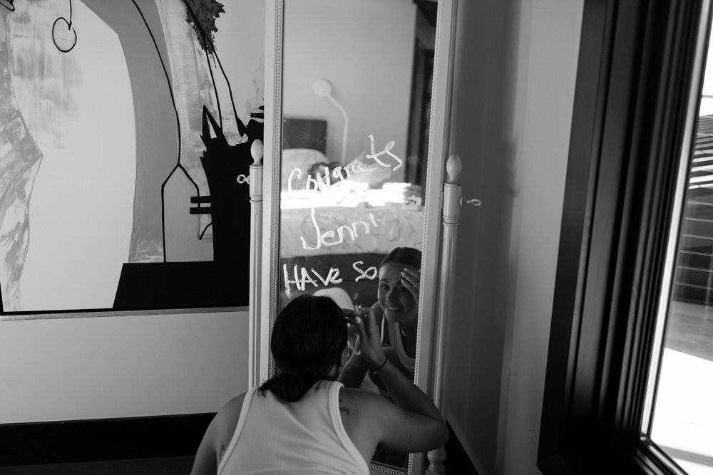 A person writes on a mirror in a black and white artistic photograph.