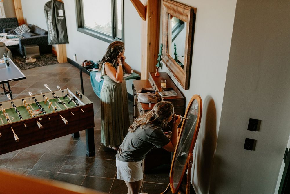 Two people play foosball in a rustic indoor setting with wooden beams.
