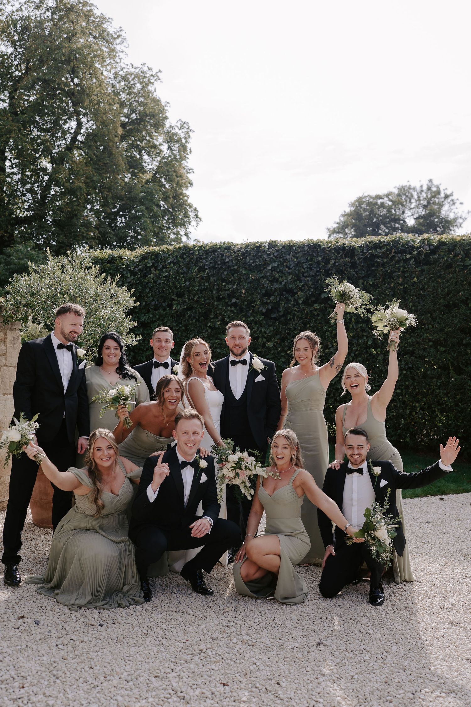 bride and groom and bridal party cheering and waving bouquets at ivy lodge in cirencester