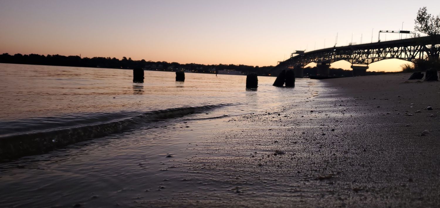 glow, after sunset seeing the sand on gloucester point beach with a silhouette of George P. Coleman bridge in the background
