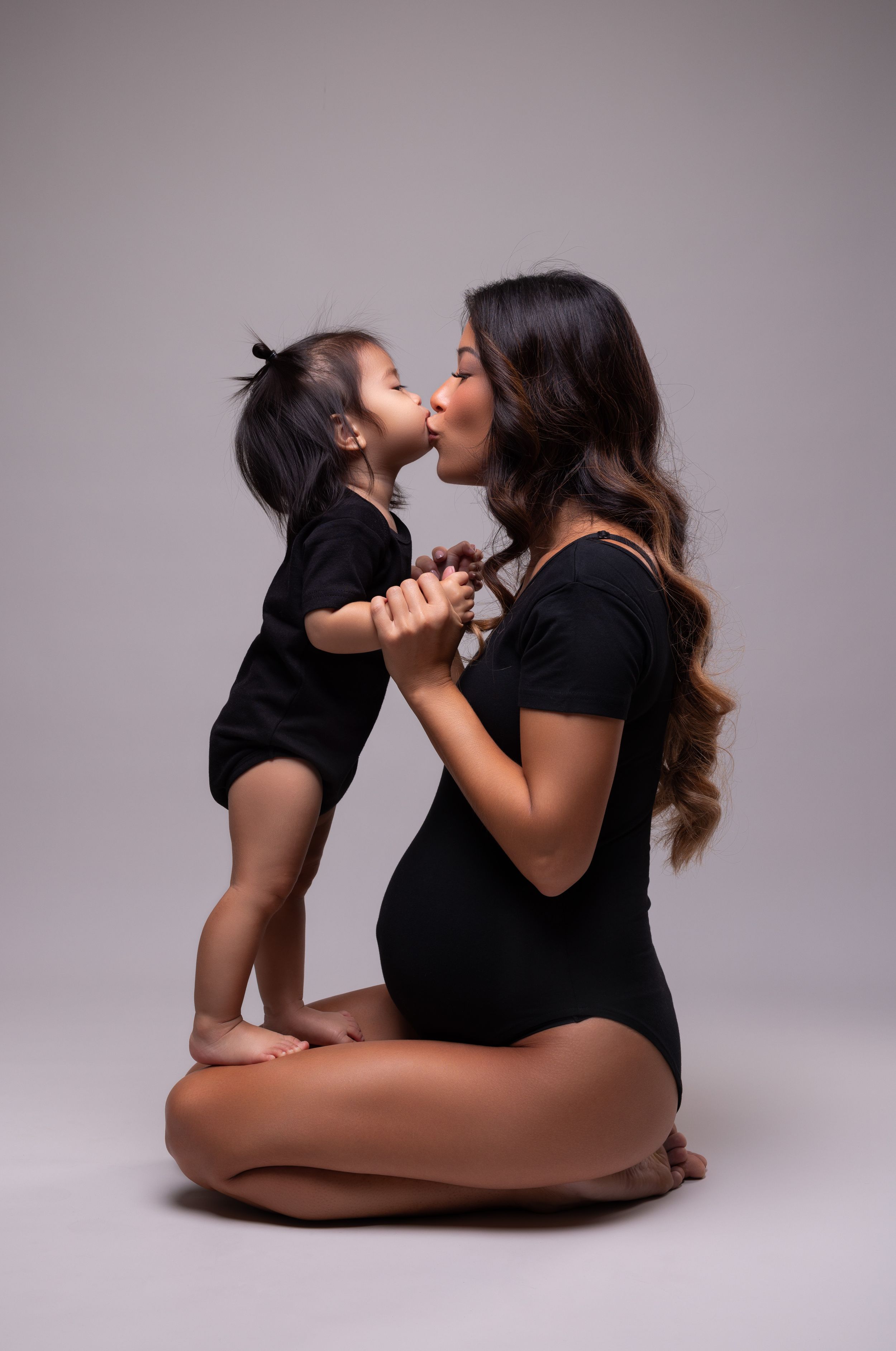 Tender moment captured between mother and child in matching black outfits.