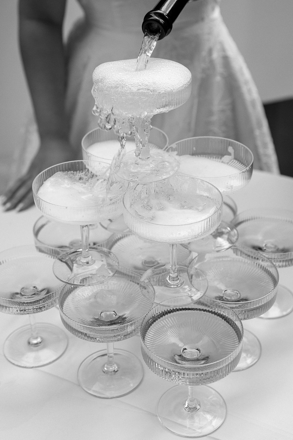 Black and white photo of champagne tower being filled at a wedding reception. Captured by Montreal wedding photographer, Aliza Dworkind.