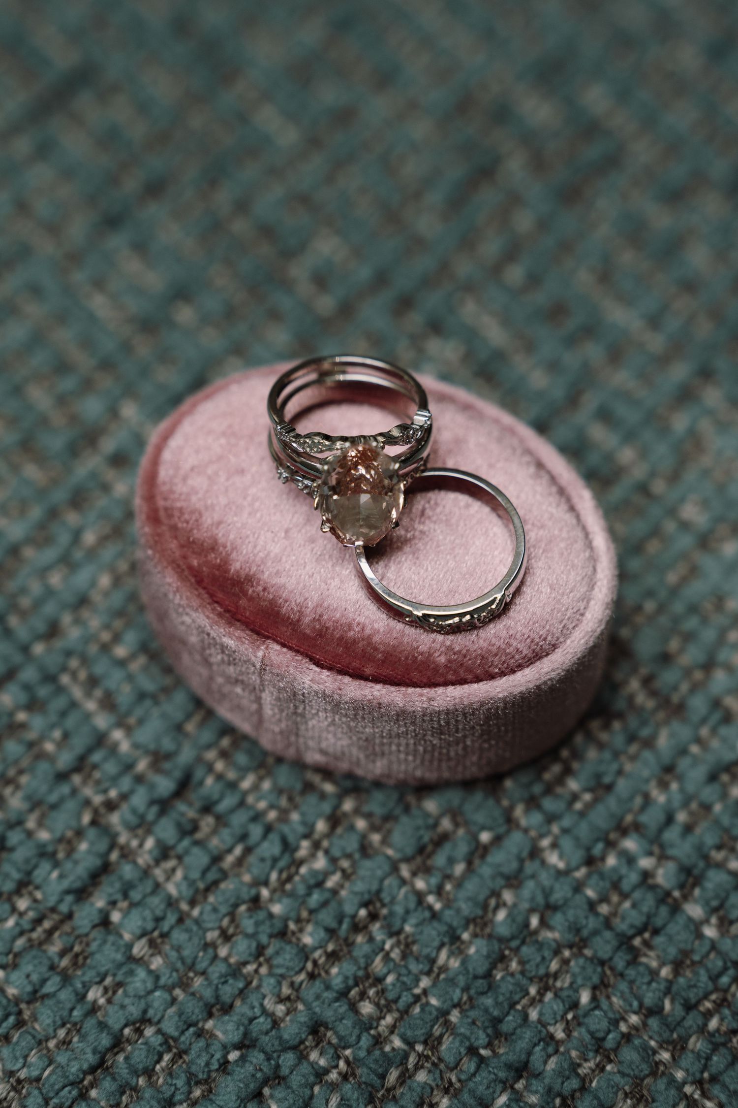 Two silver wedding rings resting on pink velvet ring box.