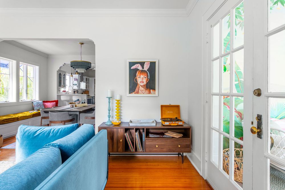 Blue sofa in a bright mid-century modern living room with hardwood floors and French doors.