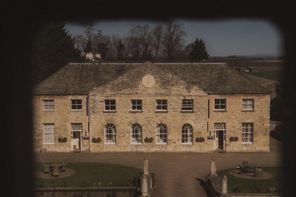 Historic stone manor house with arched windows and symmetrical facade, viewed from above on a clear day.