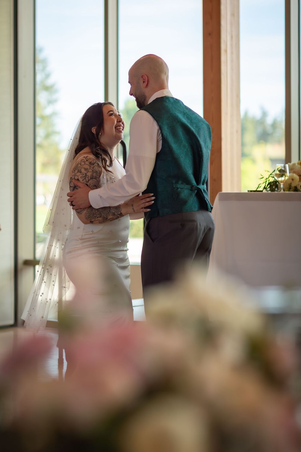 Bride and groom sharing first dance near large windows at their wedding reception.