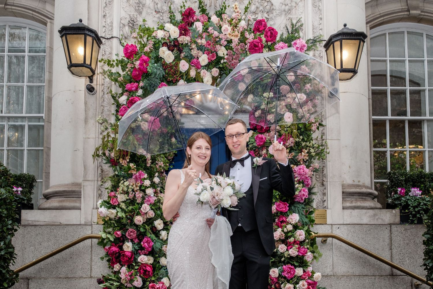 A large group of people, including a bride and groom, posing together outside a building.