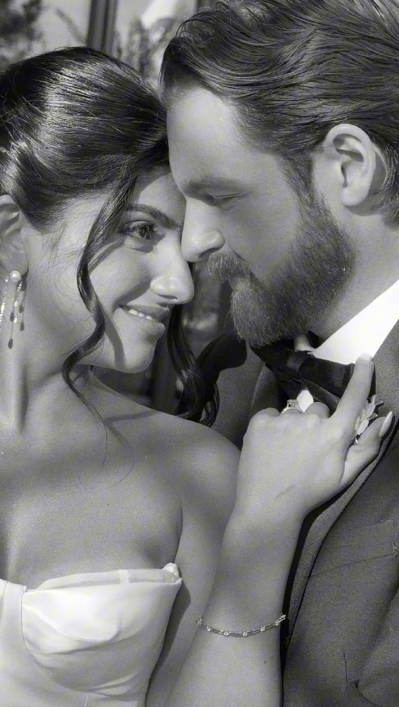 Black and white photo of a smiling bride and bearded groom sharing an intimate moment at their wedding.