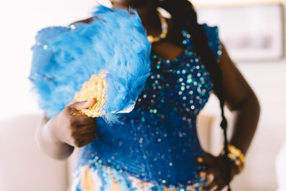 Woman in blue sequin costume holds a blue feather fan, showcasing vibrant carnival attire.