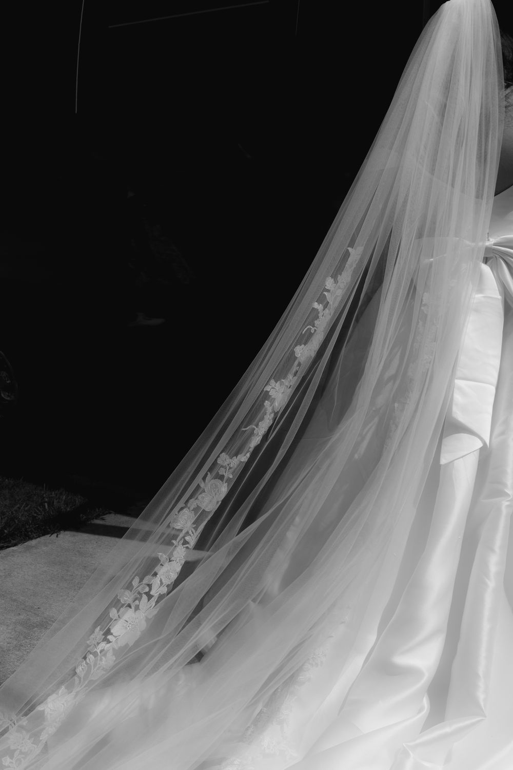Elegant bridal wedding veil with delicate lace trim flowing gracefully in black and white photo.