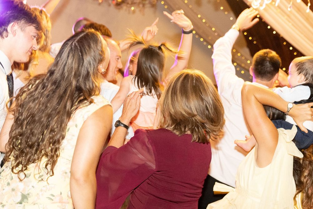 Guests dancing and celebrating joyfully at an elegant wedding reception with warm lighting.