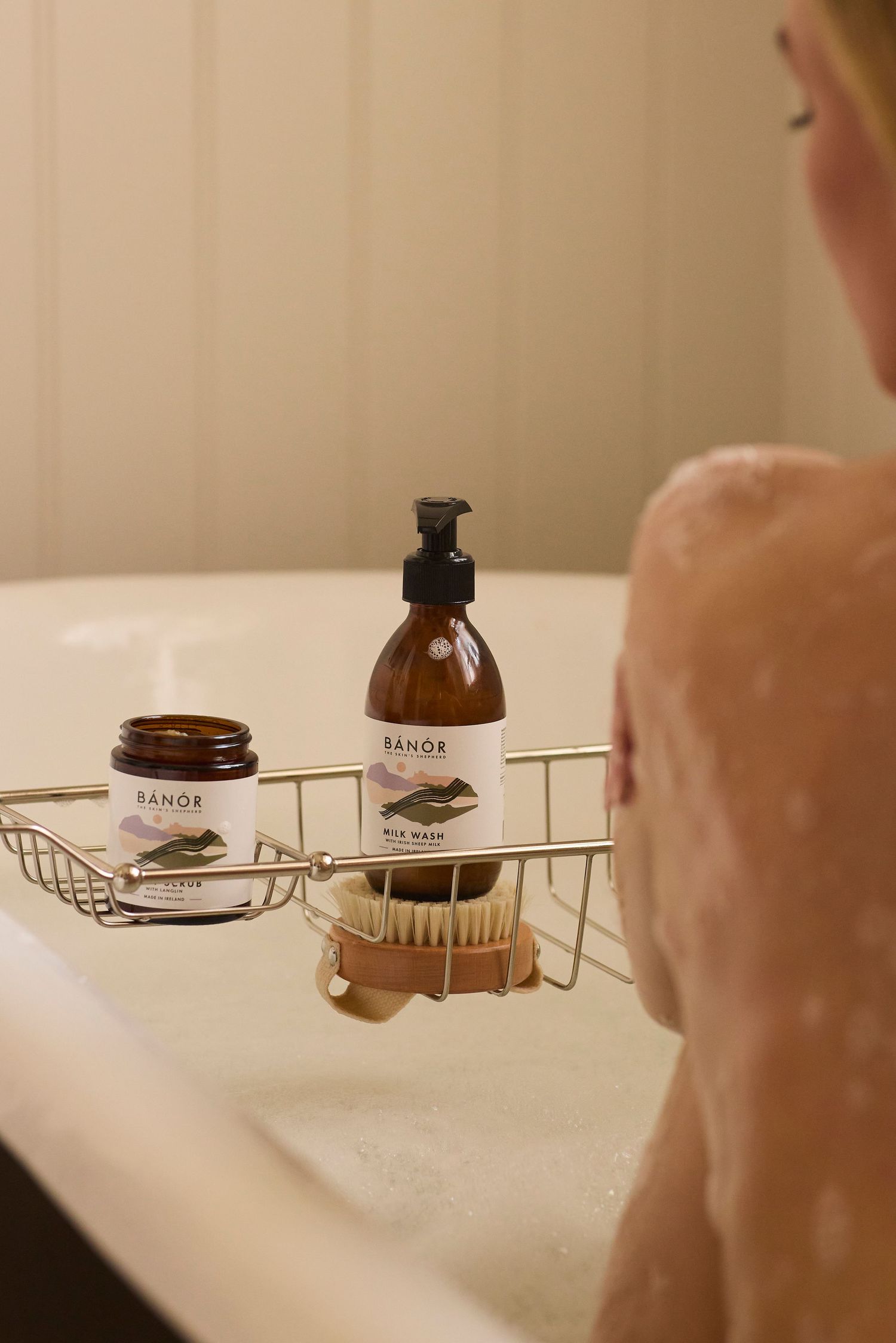 Two BANOR amber glass bottles, Milk Lotion and Body & Hair Oil, displayed on a marble surface in soft natural light.