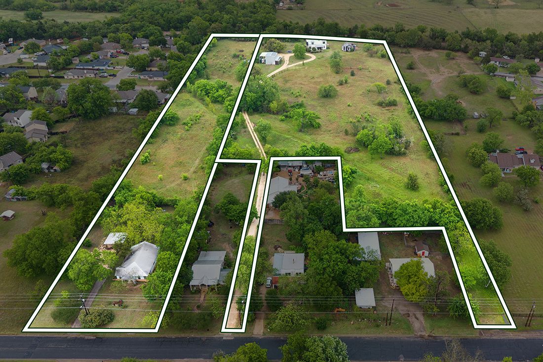 Aerial view of two residential land parcels outlined in white, surrounded by trees and homes in a suburban Texas neighborhood.