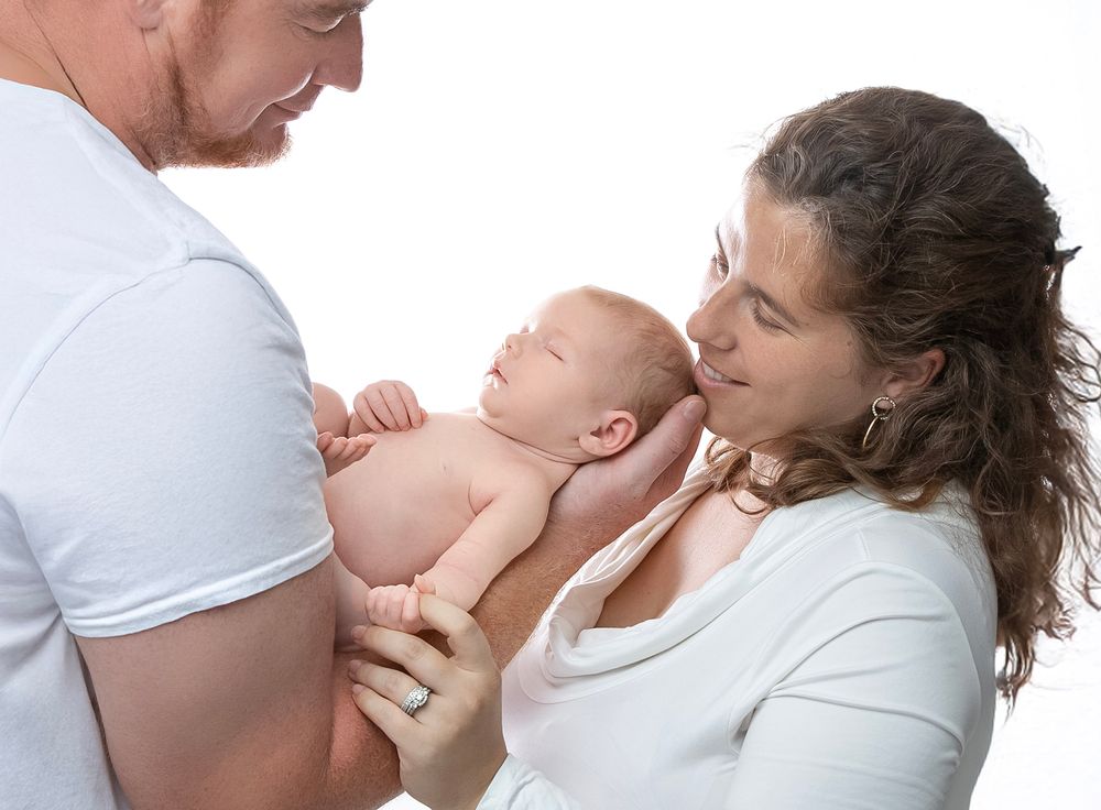 newborn baby girl with parents soft light Lakewood ranch family studio portrait emotional connection natural calm moment