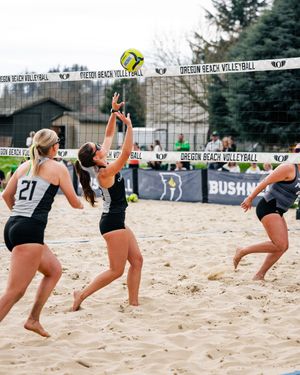 Women playing beach volleyball at Oregon Beach Volleyball tournament, with players jumping at the net on sandy court.