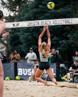 Female beach volleyball player sets the ball at an Oregon Beach Volleyball tournament on a sandy court.