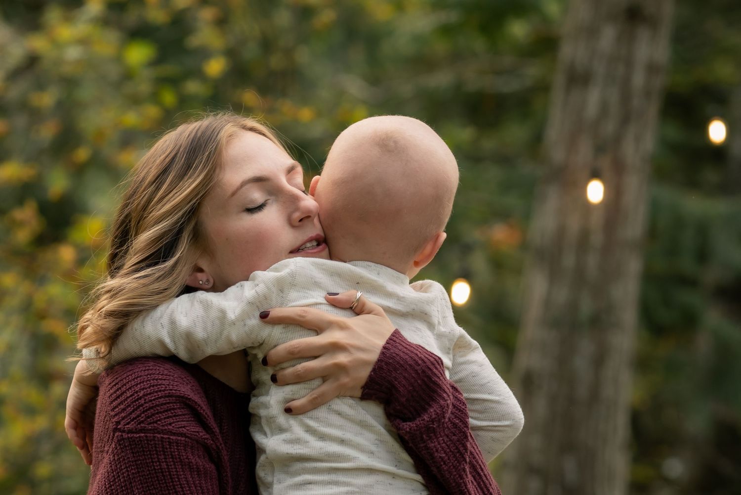 Intimate family moment captured during golden hour in wooded setting.