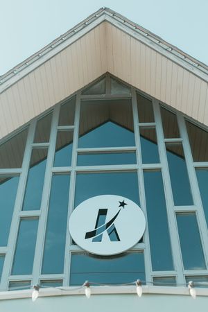Low angle view of a modern building facade with blue glass windows and a circular K logo with a star.