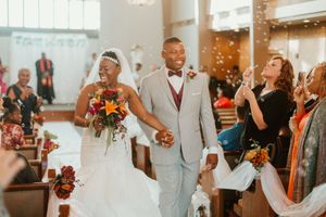 Newlywed couple walks down aisle as guests celebrate with confetti.