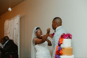 Bride playfully feeds groom wedding cake at reception celebration.