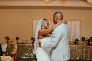 Bride and groom share their first dance in a warmly lit wedding reception venue.