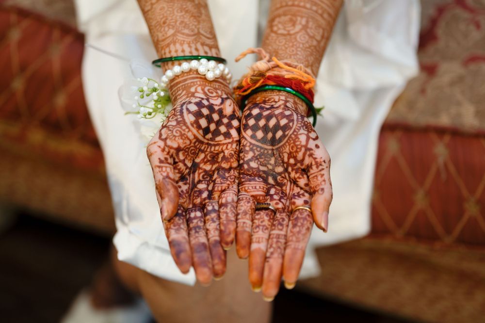 Close-up of bride's hands adorned with intricate traditional henna mehndi designs for Indian wedding ceremony.