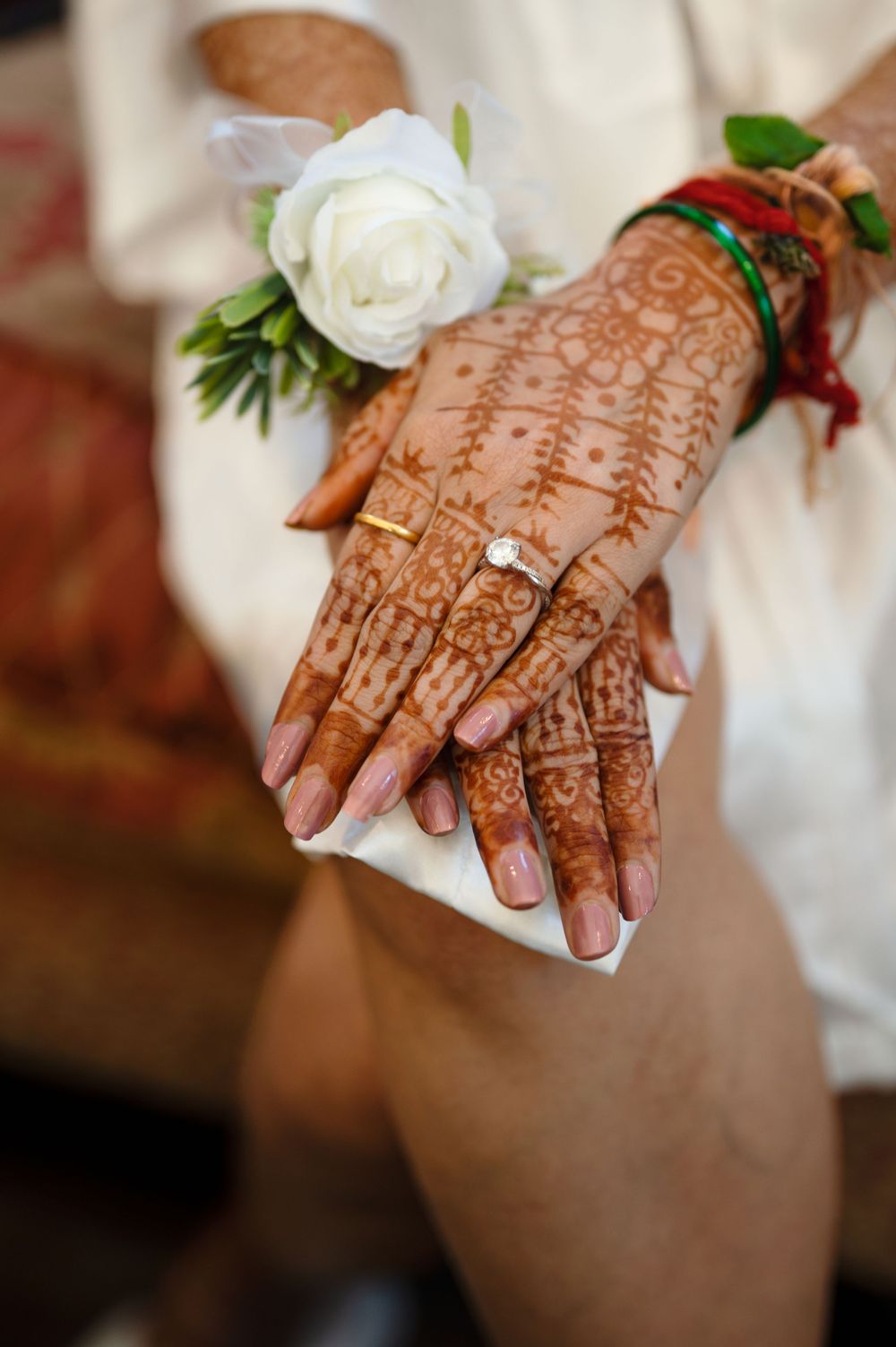 Bride's hands adorned with intricate henna mehndi design and gold engagement ring.