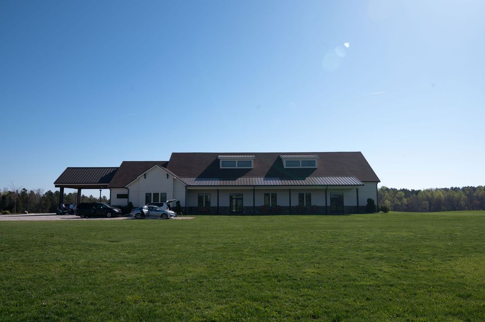 Large country building with green lawn, parked cars, and a clear blue sky backdrop.